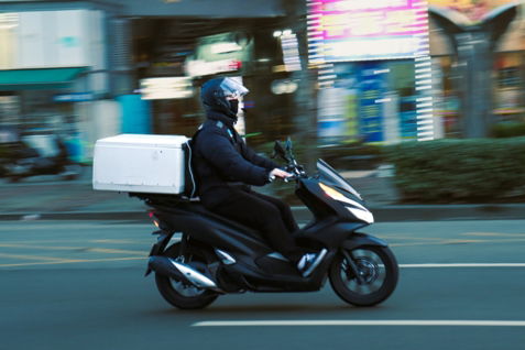 a man riding a scooter with a box on the back of it